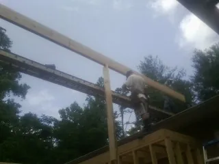 Carpenter setting a ridge beam over a new addition frame — Ice Dam Removal by Roofing Brothers in Bradford