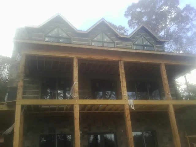 Dormers and porch framing on a large log home under construction — Roof Coating work by our crew in Bradford