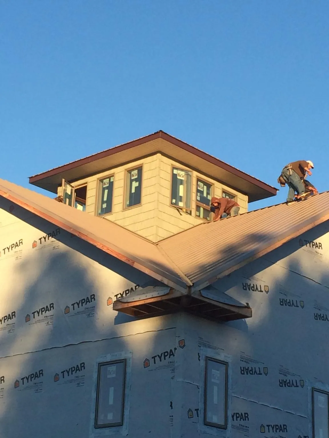 Roofers working around a rooftop cupola on a new metal roof at sunset — Roof Waterproofing in Bradford by Roofing Brothers